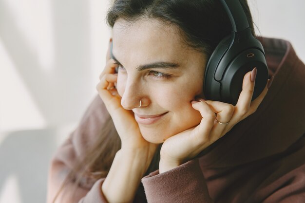 Glückliches Mädchen in den Kopfhörern hört Musik zu Hause