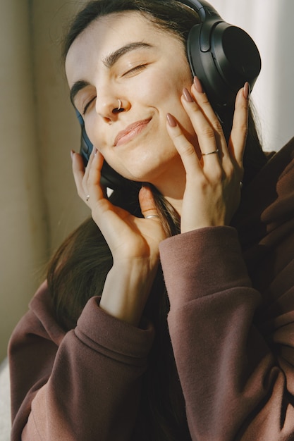 Glückliches Mädchen in den Kopfhörern hört Musik zu Hause