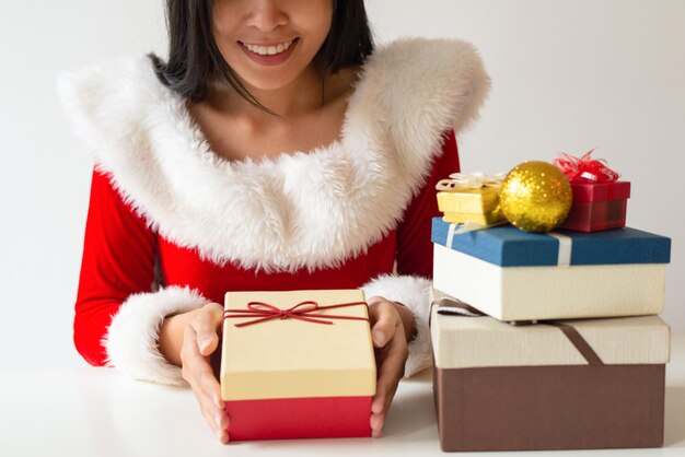 Glückliches Mädchen in Sankt-Kostüm Weihnachtsgeschenke verzierend