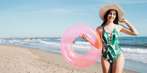 Glückliches Mädchen mit aufblasbarem Ring am Strand