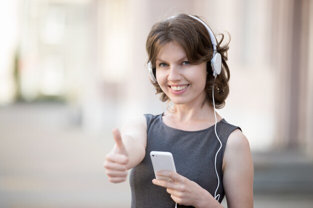 Glückliches Mädchen mit Kopfhörern eine positive Geste
