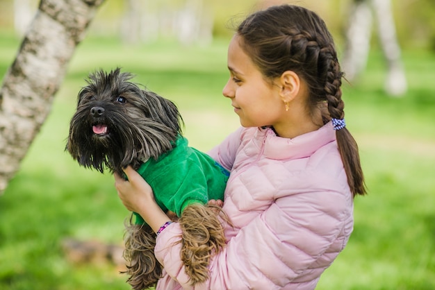 Glückliches Mädchen umarmt ihren Hund im Freien