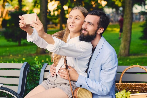 Glückliches modernes Paar bei einem Date macht Selfie in einem Park.