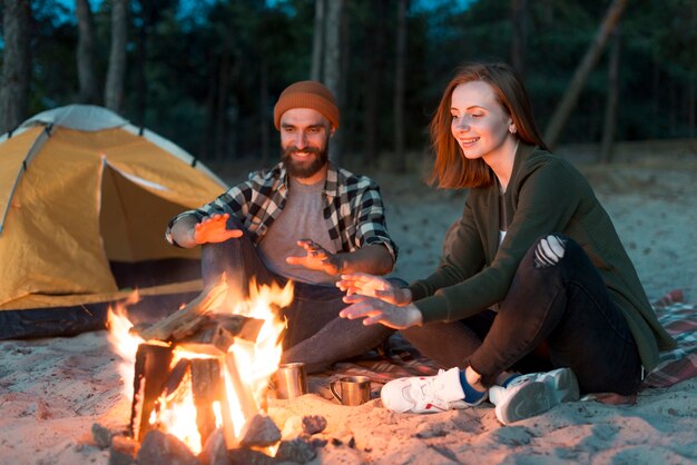 Glückliches Paar am Lagerfeuer aufwärmen