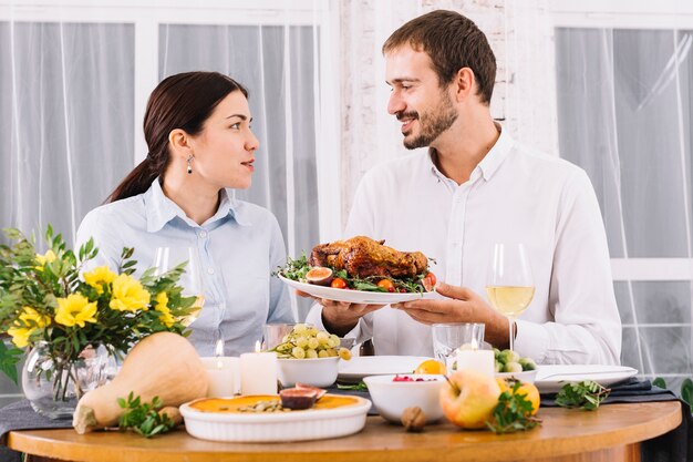 Glückliches Paar, das am festlichen Tisch spricht