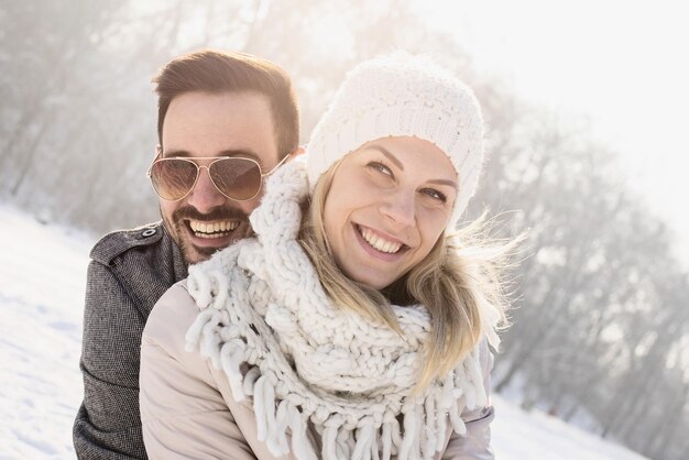 Glückliches Paar, das den schönen Schnee genießt, der an einem kalten und verschneiten Tag eingefangen wurde