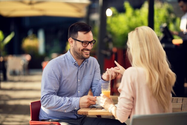 Glückliches Paar, das Händchen hält und kommuniziert, während es auf einem Date in einem Café ist Der Fokus liegt auf dem Menschen