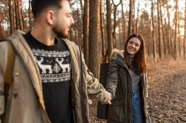 Glückliches Paar, das Hände im Wald hält