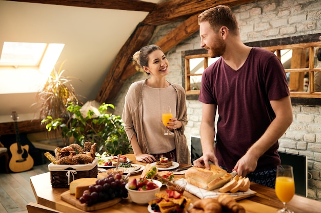 Glückliches Paar, das kommuniziert, während es das Frühstück im Speisesaal zubereitet