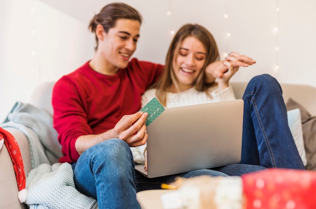 Glückliches Paar, das Laptop auf Couch verwendet