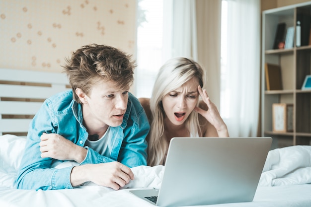 Glückliches Paar, das Laptop-Computer auf dem Bett verwendet