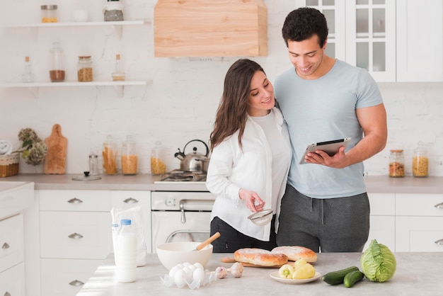 Glückliches Paar, das lernt, wie man von Online-Rezepten kocht