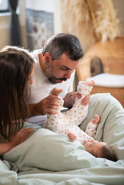 Glückliches Paar, das mit dem kleinen Sohn im Bett spielt