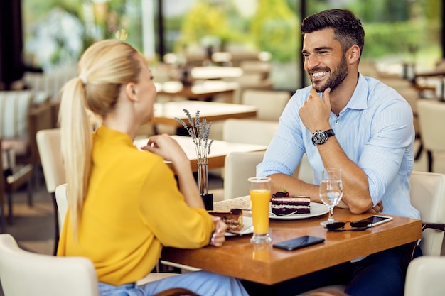 Glückliches Paar, das sich beim Dessert in einem Café unterhält