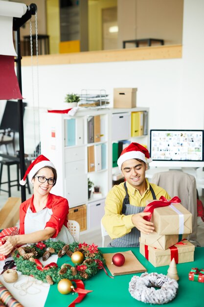 Glückliches Paar, das Weihnachtsgeschenke und -dekorationen vorbereitet