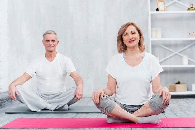 Glückliches Paar, das zu Hause auf Yogamatte sitzt