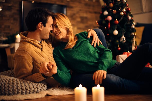Glückliches Paar, das Zuneigung zeigt, während es sich am Weihnachtsabend zu Hause entspannt