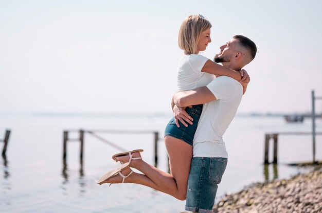 Glückliches Paar, das zusammen am Strand hängt