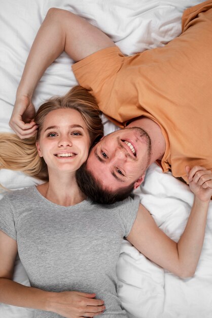 Glückliches Paar der Draufsicht, das in Bett legt