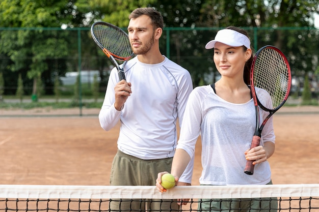 Glückliches Paar der Vorderansicht auf Tennisplatz