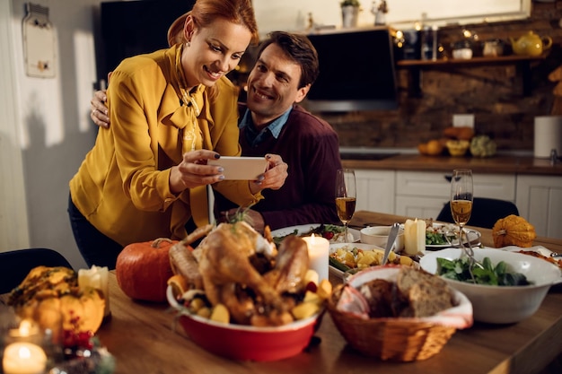 Glückliches Paar feiert Thanksgiving und fotografiert den zum Abendessen gedeckten Esstisch