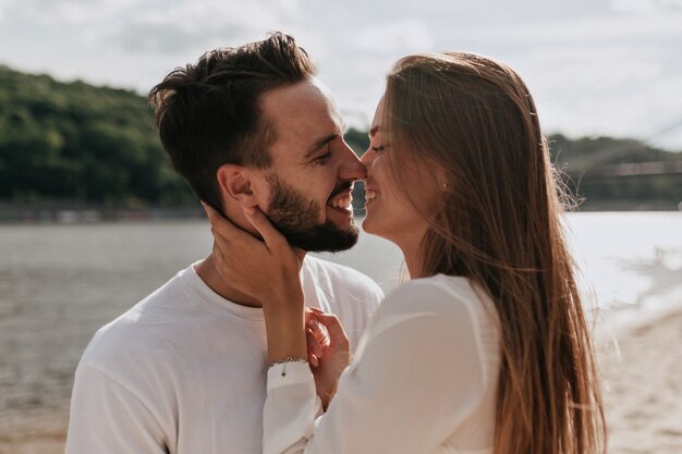 Glückliches Paar in der Liebe, die zusammen am Strand an einem warmen sonnigen Tag umarmt und küsst