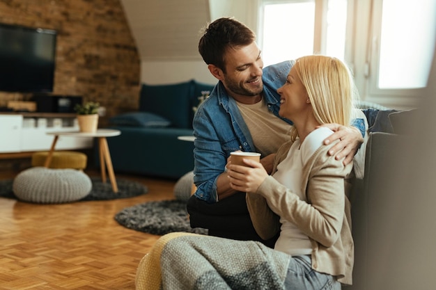 Glückliches Paar kommuniziert, während es im Wohnzimmer nahe beieinander sitzt