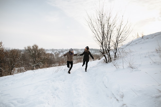 Glückliches Paar lässt das Händchenhalten an einem Tag des verschneiten Winters laufen. Winterliebe. Liebesgeschichte.