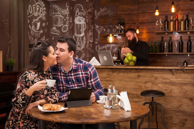 Glückliches Paar mit digitalem Tablet beim Kaffeetrinken im Restaurant. Hipster-Restaurant.