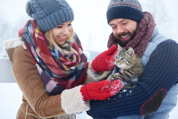 Glückliches Paar mit Katze im Wintertag