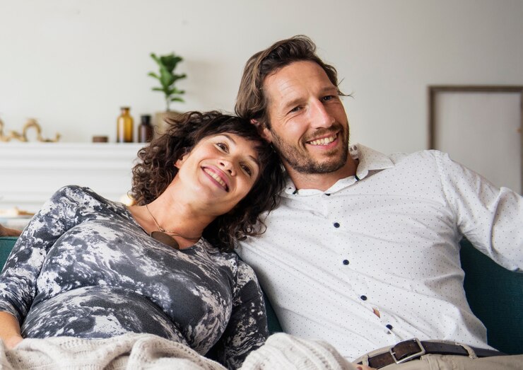 Kostenlose Foto glückliches schwangeres paar, das sich im wohnzimmer aufeinander stützt