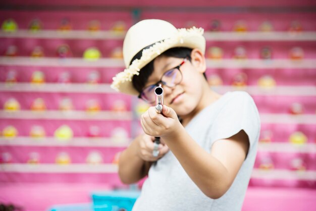 Glückliches spielendes Puppengewehrtrieb des asiatischen Jungen im lokalen Spaßpark-Festivalereignis, Leute mit glücklicher Tätigkeit