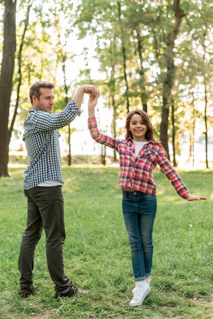 Glückliches Vater- und Tochtertanzen im Garten