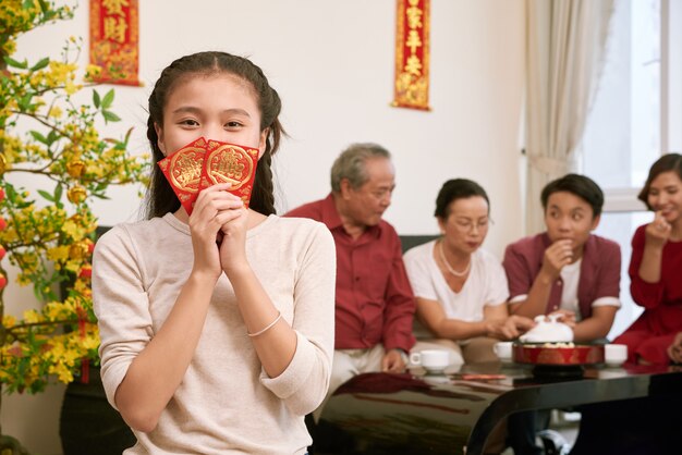 Glückliches vietnamesisches Mädchen, das Umschläge mit hält