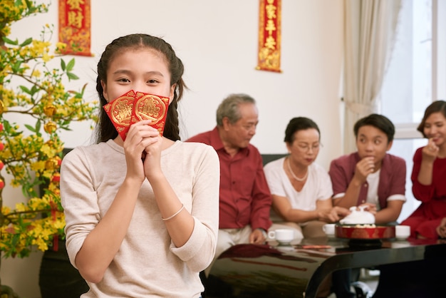 Glückliches vietnamesisches Mädchen, das Umschläge mit hält