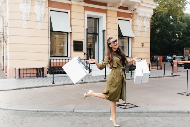 Glückselige shopaholic Frau, die auf der Straße mit Lächeln tanzt