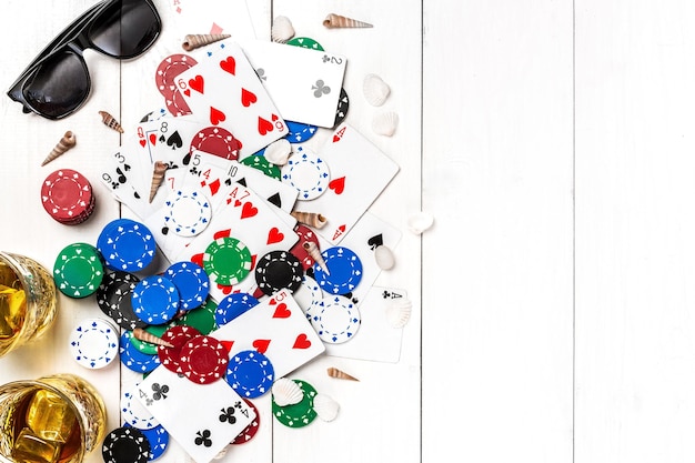Glücksspiel. Pokerchips, Karten und das Würfeltablett in der Nähe auf weißem Holztisch. Ansicht von oben. Exemplar. Poker. Sommer. Sonneneruption