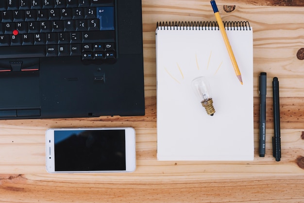 Glühbirne auf Notebook in der Nähe von Technologien