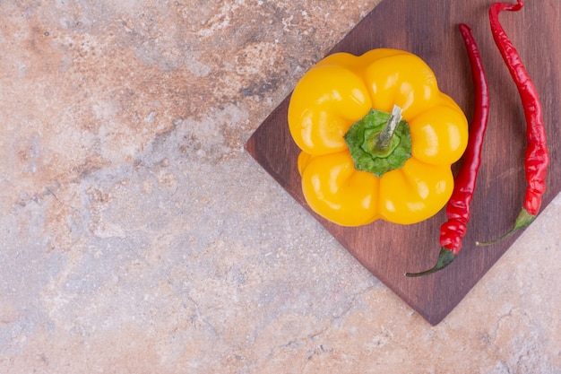 Kostenloses Foto glühende chilis mit gelbem paprika auf einem holzbrett.