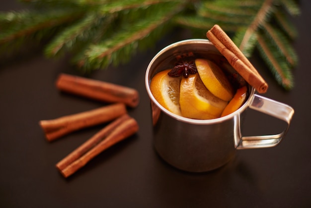 Glühwein auf schwarzem Tisch mit Tannenzweigen trinken