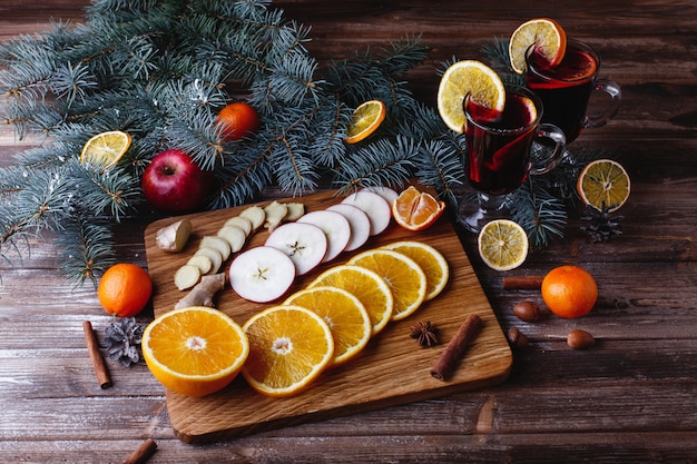 Glühwein kochen. Orangen, Äpfel und Arten liegen auf Holztisch