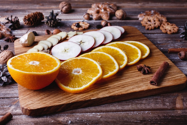 Glühwein kochen. Orangen, Äpfel und Arten liegen auf Holztisch