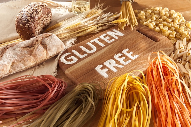 Glutenfreies Essen. Verschiedene Nudeln, Brot und Snacks auf hölzernem Hintergrund von oben. Gesundes und Diät-Konzept.