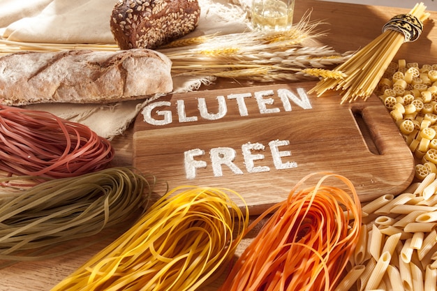 Glutenfreies Essen. Verschiedene Nudeln, Brot und Snacks auf hölzernem Hintergrund von oben