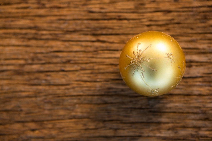 Kostenlose Foto goldene kugel auf einem holztisch