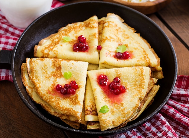 Goldene Pfannkuchen mit Preiselbeermarmelade und Honig im rustikalen Stil. Ansicht von oben