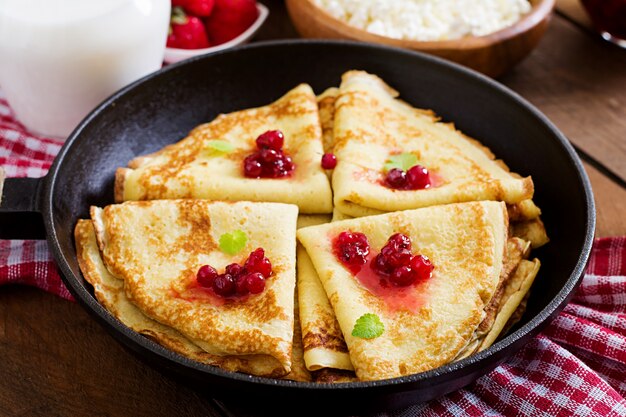 Goldene Pfannkuchen mit Preiselbeermarmelade und Honig im rustikalen Stil. Ansicht von oben