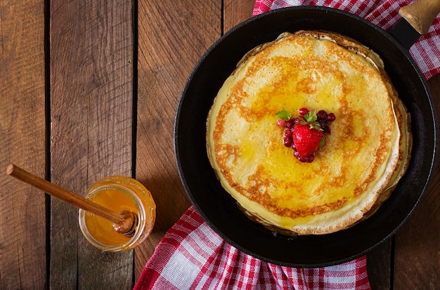 Goldene Pfannkuchen mit Preiselbeermarmelade und Honig im rustikalen Stil. Ansicht von oben