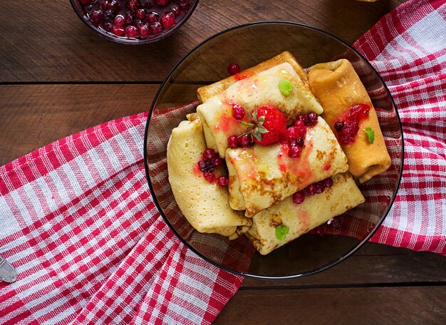 Goldene Pfannkuchen mit Preiselbeermarmelade und Honig im rustikalen Stil. Ansicht von oben