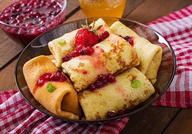 Goldene Pfannkuchen mit Preiselbeermarmelade und Honig im rustikalen Stil. Ansicht von oben